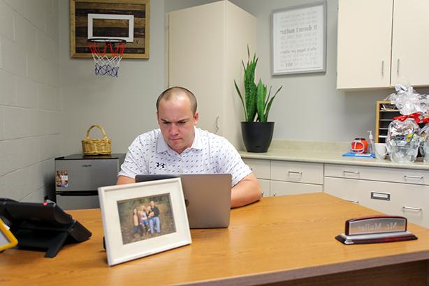 Elementary school principal sitting at a computer in his office